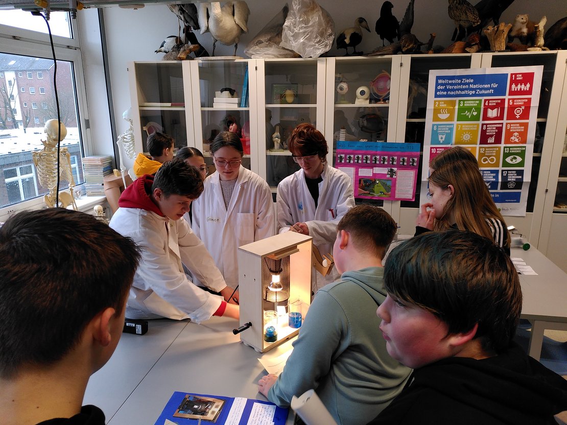 Foto Schüler*innen an Experimentaufbau