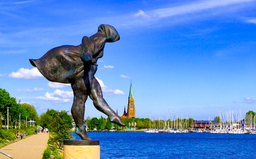 Foto der Skulptur "Schleswigerin" mit Blick auf den Hafen und den Schleswiger Dom