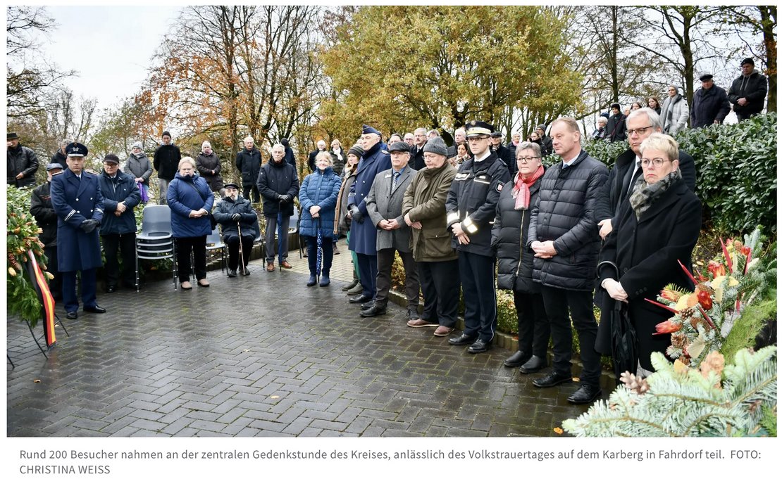 Mehrere Personen stehen im Halbkreis am Volkstrauertag.